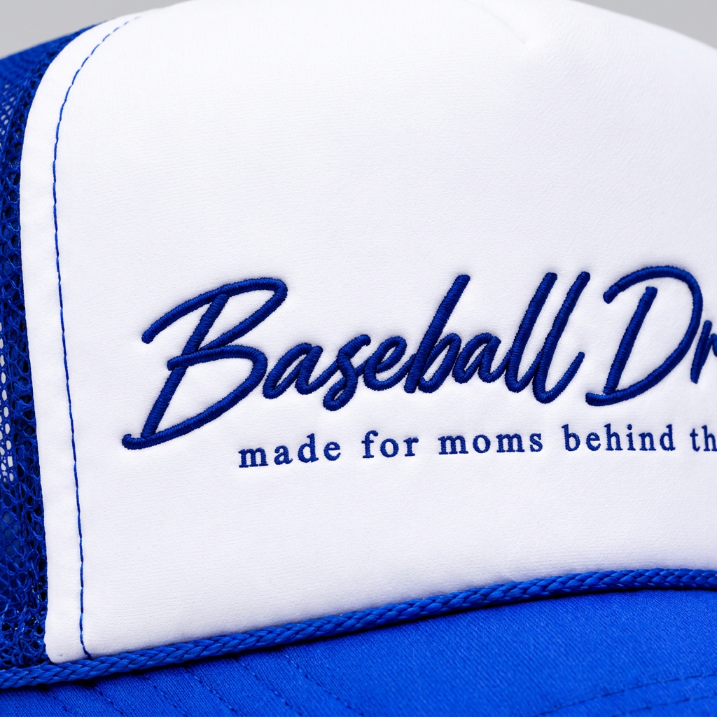 Close-up of the Baseball Dreamz embroidered logo on the blue and white Game Day Trucker hat